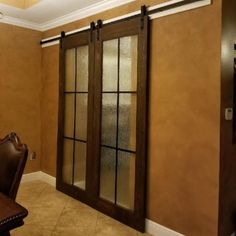 a dining room table and chairs with sliding glass doors on the wall behind them, in front of a brown leather chair