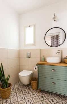 a white toilet sitting next to a sink in a bathroom under a mirror and a potted plant