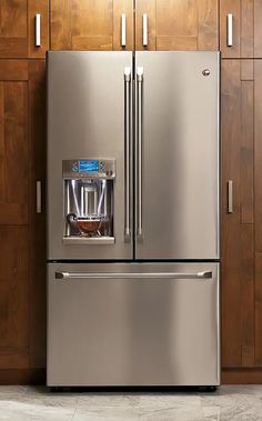 a metallic refrigerator freezer sitting inside of a kitchen next to wooden cabinets and drawers