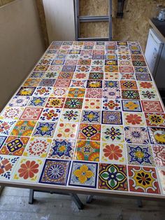 a kitchen table with colorful tiles on it in the process of being painted by someone