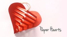 a red heart shaped origami hanging from a string with the words paper hearts on it