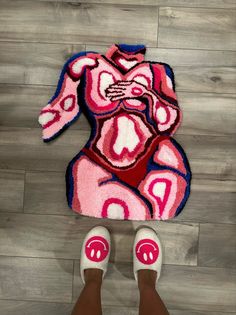 someone is standing on the floor with their feet up in front of a rug that looks like a woman's torso