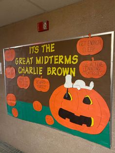 a bulletin board with pumpkins on it in a school hallway that reads, its the great midterms charlie brown