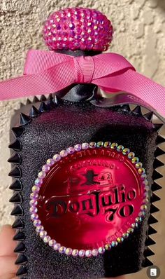 the bottle is decorated with pink and purple beads on it's cap, which has a bow at the top