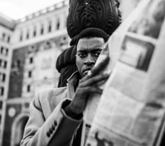 a man reading the paper while standing in front of a building