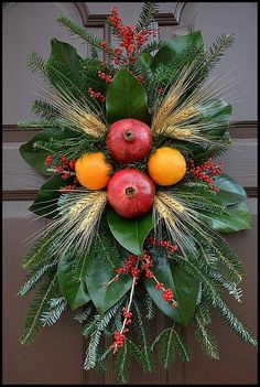 a wreath with apples, oranges and leaves on the front door's side