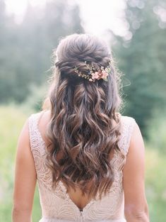 the back of a woman's head with long hair and flowers in her hair