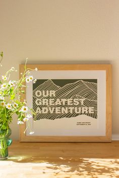 a vase filled with flowers sitting on top of a table next to a framed poster