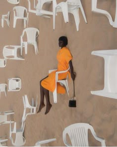 a woman in an orange dress is sitting on a white chair and looking down at the ground