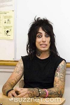 a man with tattoos sitting at a desk