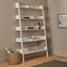 a white book shelf with books on it in a living room next to a rug