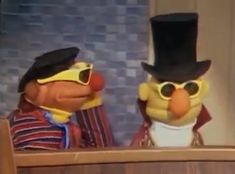 two cartoon characters wearing hats and sunglasses, one is talking to the other while sitting at a table