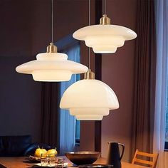 three lights hanging over a dining table in a room with dark walls and wooden floors