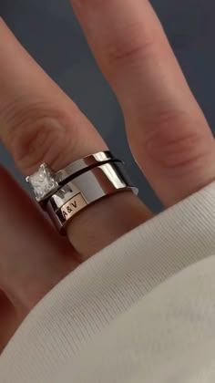 a close up of a person's hand with two rings on their fingers and one has a diamond in the middle