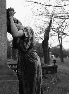 a statue is standing in the middle of a cemetery