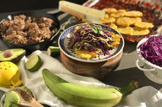 a table topped with bowls filled with food and veggies next to other foods