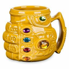 a yellow ceramic mug with colorful stones on it