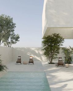 two wooden chairs sitting on top of a pool next to a tall white building with trees in the background