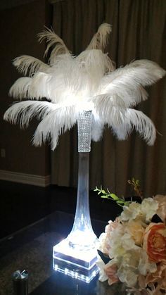 a table topped with a vase filled with flowers and a light up palm tree on top of it