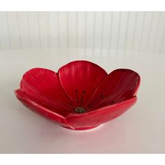 a red flower shaped bowl sitting on top of a table