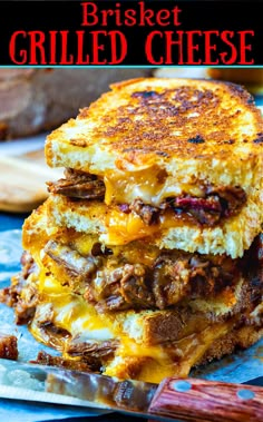 a stack of three sandwiches sitting on top of a cutting board next to a glass of beer