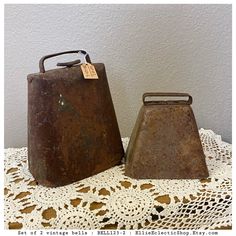 two rusty metal containers sitting on top of a doily