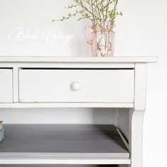 a white table with drawers and a vase on top