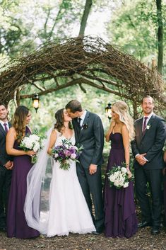 a bride and groom kissing with their bridals in front of an arch made of branches