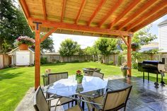 an outdoor dining area with grill, table and chairs