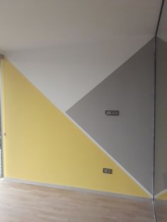 an empty room with yellow, grey and white paint on the wall next to a window