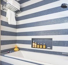 a bathroom with blue and white tiles on the wall, tub and towel rack in the corner