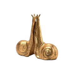 two golden snails are standing next to each other on a white background, one has its head up and the other is upside down