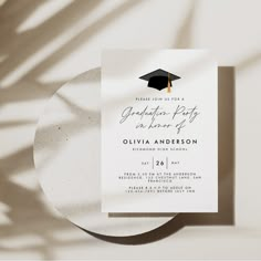 a graduation party card with a black and gold tassel on the front, next to a white plate