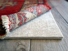 a rug laying on top of a wooden floor next to a red and blue rug