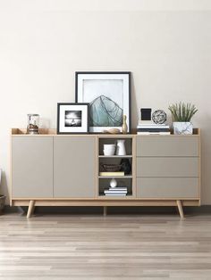 a sideboard with some pictures on top of it and a plant next to it