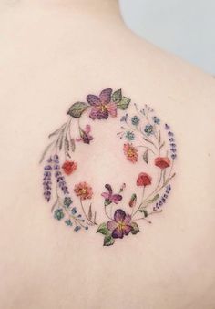 the back of a woman's shoulder with colorful flowers and leaves in a circle