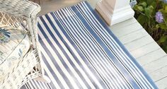 a blue and white striped rug sitting on top of a wooden floor next to a chair