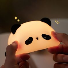 someone is holding up a lamp that looks like a panda bear's head with eyes