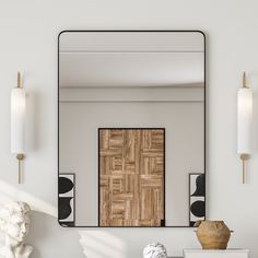 a mirror sitting on top of a wall next to a vase