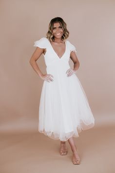 a woman in a white dress posing for the camera with her hands on her hips