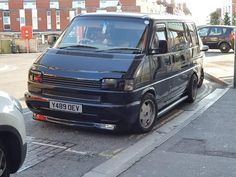 a van parked on the side of a street next to a curb with other cars