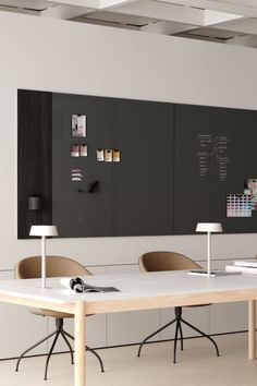 a table with two chairs and a blackboard on the wall in an office setting