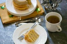 there is a piece of cake on the plate next to a cup of tea and silverware