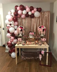 a table topped with lots of balloons next to a pink and white cake covered in flowers