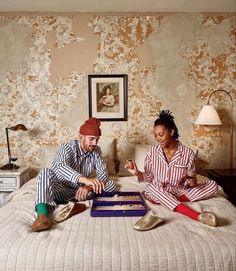 two people sitting on top of a bed next to each other in pajamas and slippers