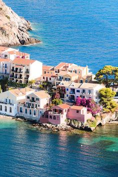 an aerial view of a small island with houses on it and clear blue water in the foreground