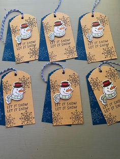 four tags with snowmen on them hanging from twine