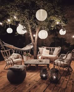 an outdoor deck with chairs, tables and lights hanging from the ceiling over it's wood flooring