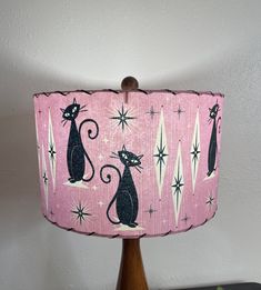 a pink lamp shade with black cats on it and stars around the lampshade