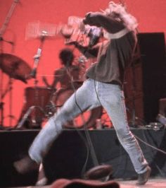 a man standing on top of a stage next to a microphone and other musical instruments